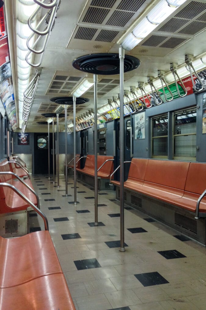 a vintage subway car with salmon pink seats and black and tan tile floor
