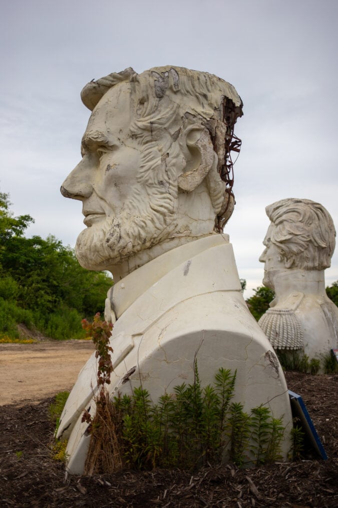 a large bust of abraham lincoln cracked and sitting in a field