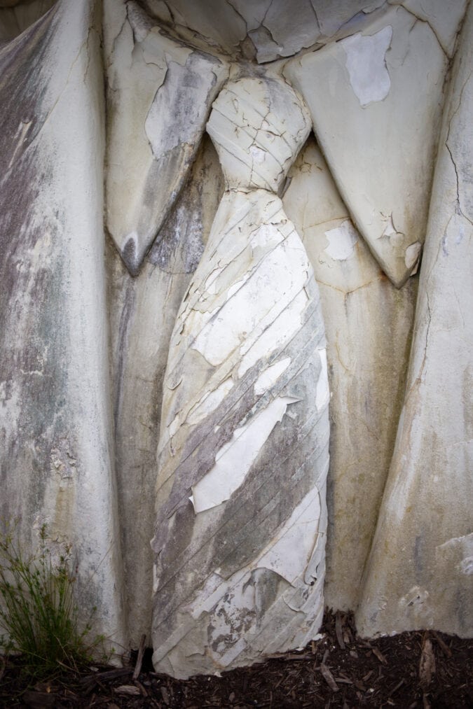 a closeup of a crumbling bust with a striped tie