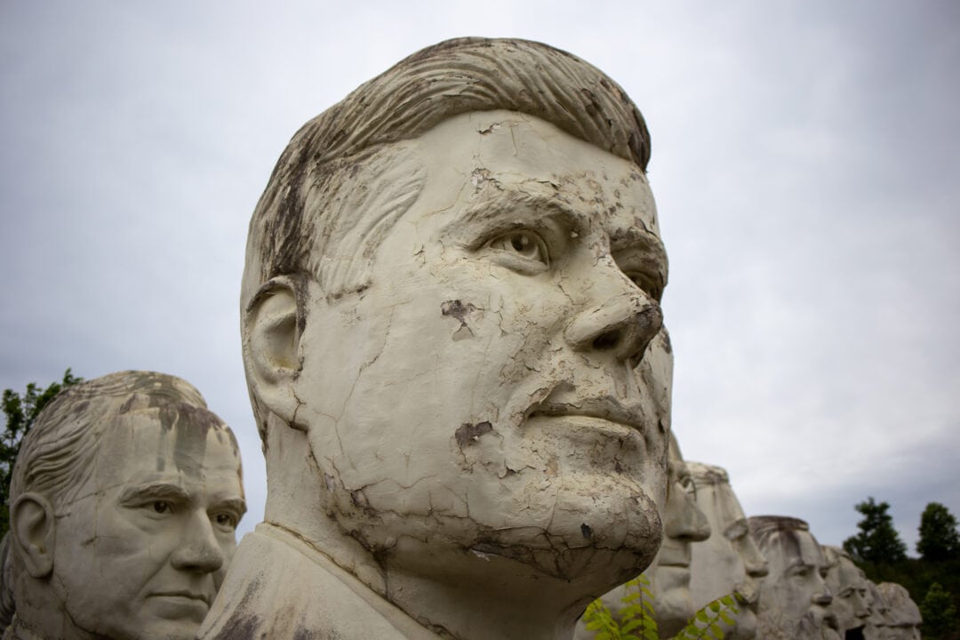 a closeup shot of a large crumbling bust of john f kennedy looking out into the distance