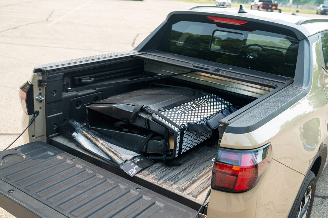a tan suv/truck hybrid with its tailgate open and stuff stored in the truck bed