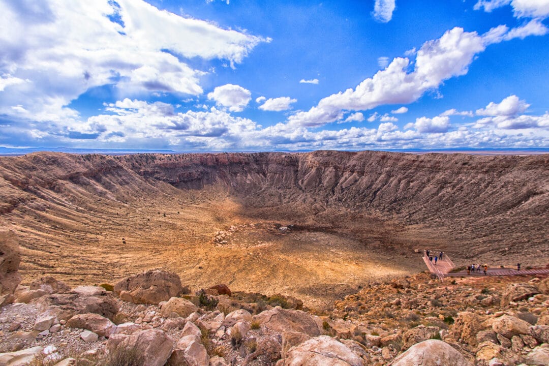 a very large crater in the desert under blue skies